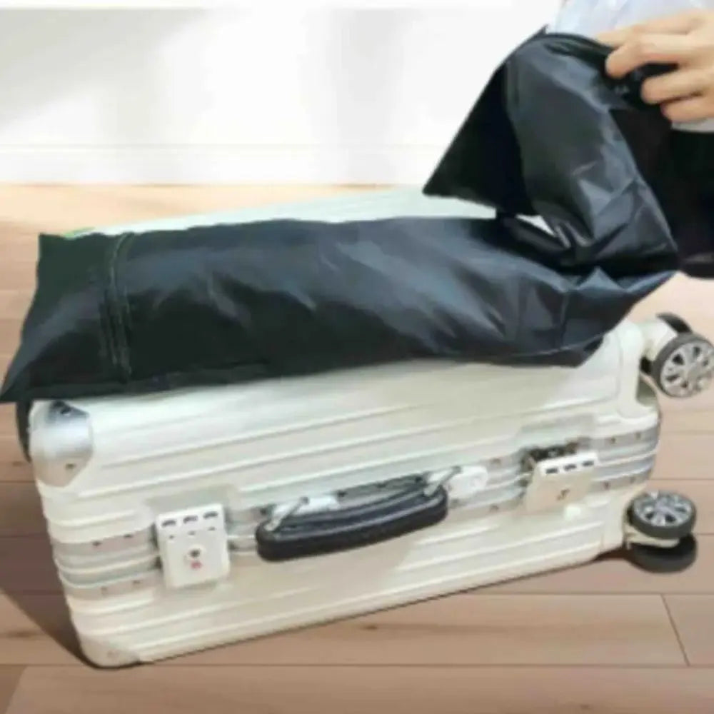 Person using a black vacuum bag to compress clothes on a suitcase.