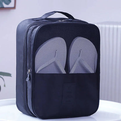 Black travel shoe bag with mesh sections for shoes on a white surface.