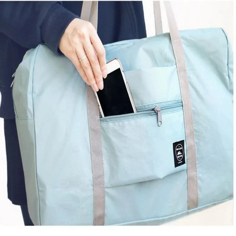 Light blue duffel bag with a hand holding a phone in a pocket, on a white background