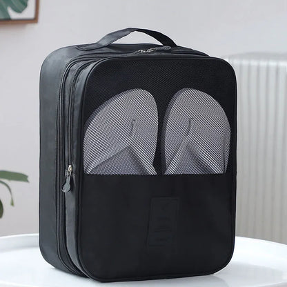 Black shoe bag with a pair of gray slippers inside on a white surface.