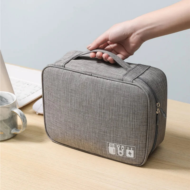 Gray travel bag with a hand holding it on a wooden surface.