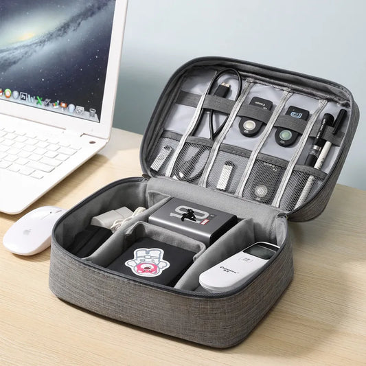 Gray travel case with electronic accessories on a desk next to a laptop.