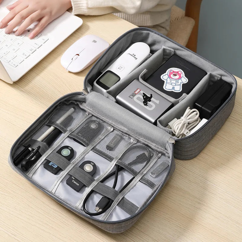 Gray travel organizer with electronic devices on a wooden desk