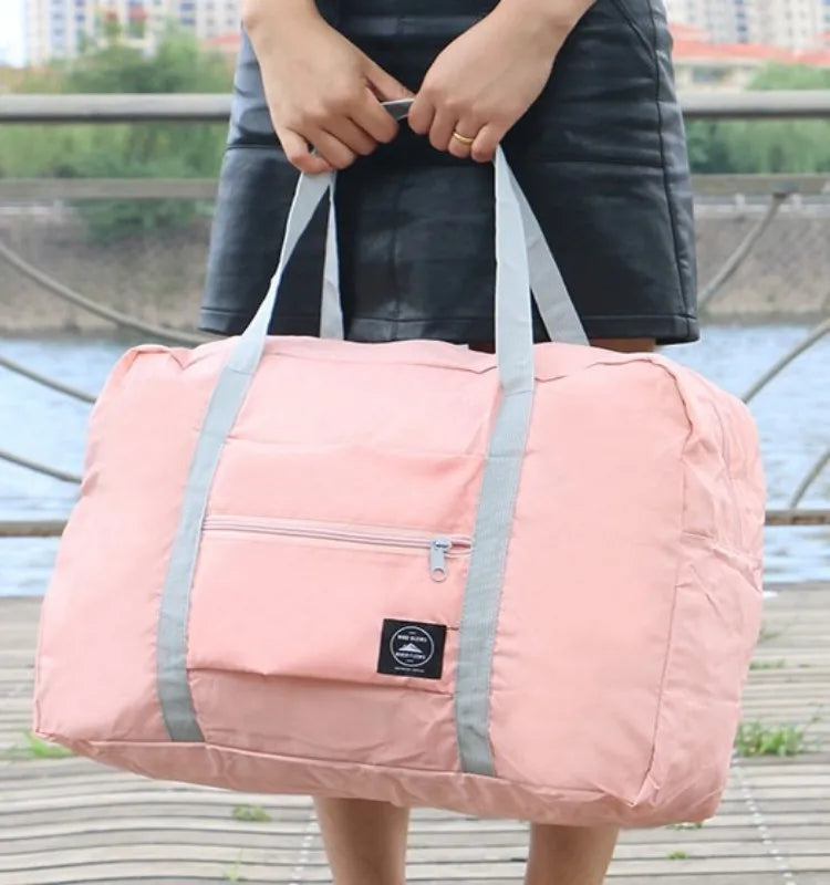 Person holding a pink duffel bag with gray straps outdoors.