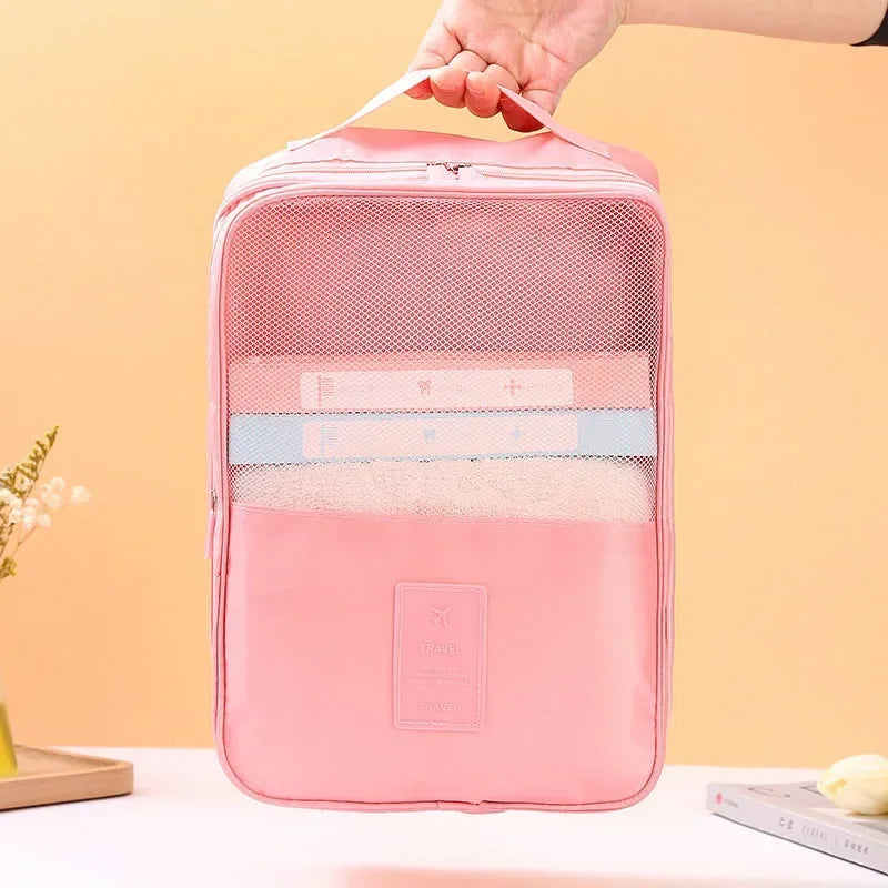 Pink travel organizer bag with a hand holding it against a peach background
